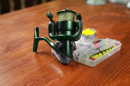 Photo for Fishing tackle. Spinning reel, lures and bait on wooden table, closeup - Royalty Free Image