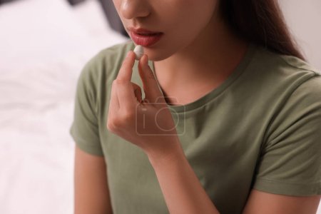 Woman taking antidepressant pill on blurred background, closeup