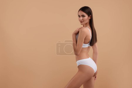 Foto de Mujer joven en elegante bikini blanco sobre fondo beige. Espacio para texto - Imagen libre de derechos