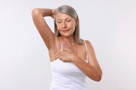 Belle femme âgée faisant l'auto-examen du sein sur fond blanc