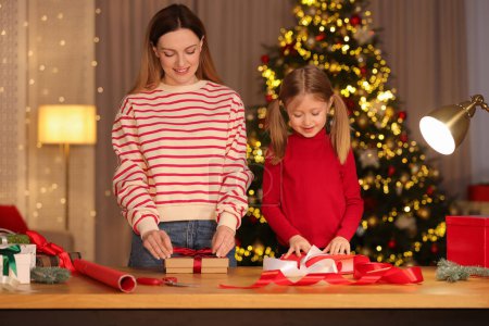 Envoltura de regalos de Navidad. Madre y su hija pequeña decorando cajas de regalo en casa