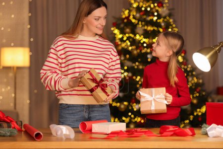 Envoltura de regalos de Navidad. Madre y su pequeña hija sosteniendo cajas de regalo en casa