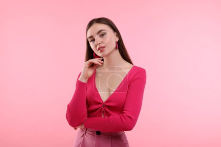 Beautiful young woman in pink clothes on color background
