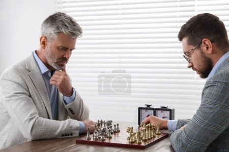 Hombres jugando ajedrez durante el torneo en la mesa en el interior