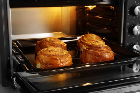 Open electric oven with delicious sweet pastry