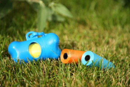 Rolls of colorful dog waste bags on green grass outdoors