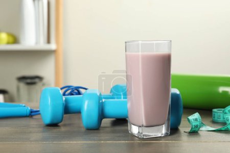 Tasty shake, sports equipment and measuring tape on wooden table indoors. Weight loss