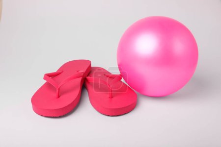 Téléchargez les photos : Ballon de plage gonflable rose et tongs sur fond blanc - en image libre de droit