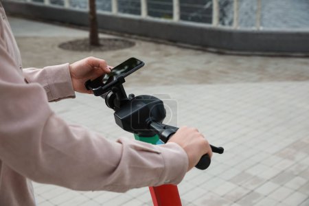 Photo for Man using smartphone to pay and unblock electric kick scooter outdoors, closeup. Space for text - Royalty Free Image