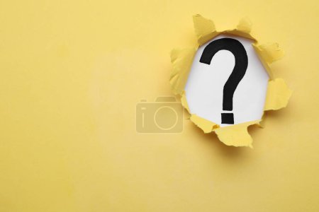 Téléchargez les photos : Point d'interrogation sur fond blanc, vue à travers un trou dans du papier jaune, espace pour le texte - en image libre de droit