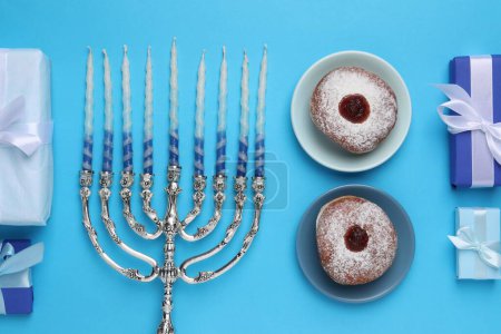Composición plana con Hanukkah menorah y rosquillas sobre fondo azul claro