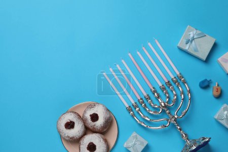 Composición plana con Hanukkah menorah y rosquillas sobre fondo azul claro, espacio para texto