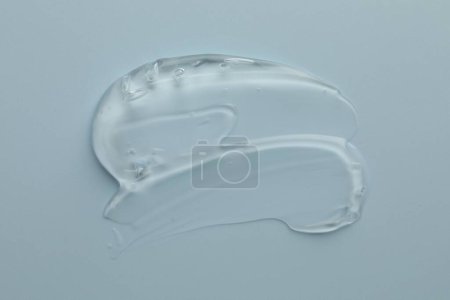 Photo for Smear of clear cosmetic gel on light blue background, top view - Royalty Free Image