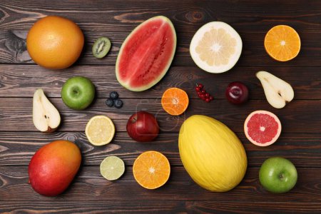 Different ripe fruits and berries on wooden table, flat lay