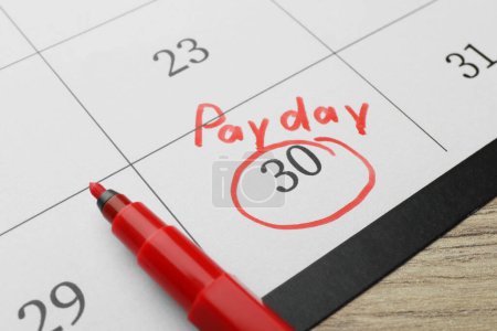 Photo for Calendar page with marked payday date and red marker on table, closeup - Royalty Free Image