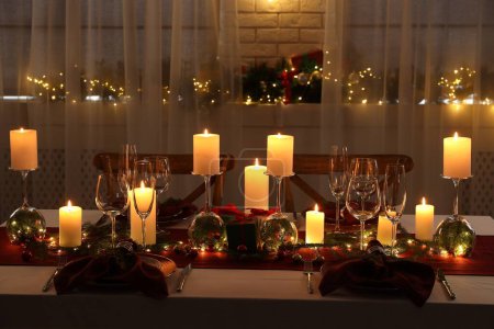 Christmas table setting with burning candles and festive decor