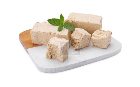 Board with pieces of tasty halva and mint isolated on white