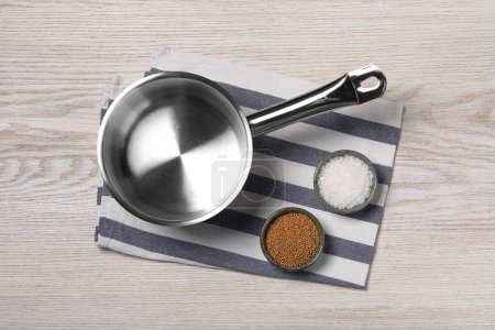 Photo for One steel saucepan and spices on white wooden table, top view - Royalty Free Image