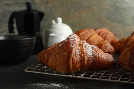 Delicious fresh croissants with powdered sugar on grey table