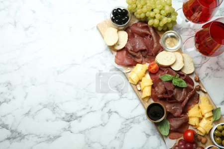 Photo for Charcuterie board. Delicious bresaola, wine and other products on white marble table, flat lay. Space for text - Royalty Free Image