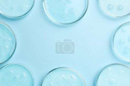 Photo for Frame of Petri dishes with liquid samples on light blue background, flat lay. Space for text - Royalty Free Image