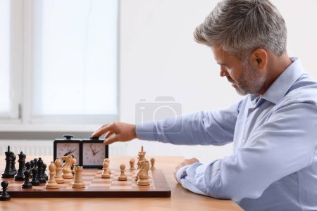 Hombre encendiendo el reloj de ajedrez durante el torneo en la mesa en el interior