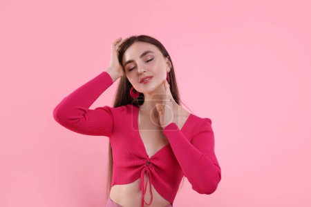 Beautiful young woman in pink clothes on color background