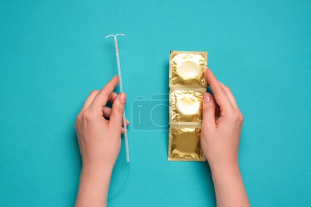 Woman with condoms and intrauterine device on light blue background, top view. Choosing birth control method