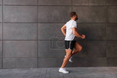 Junger Mann läuft in der Nähe von Gebäuden im Freien. Raum für Text