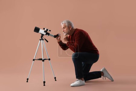 Astronome senior avec télescope sur fond brun