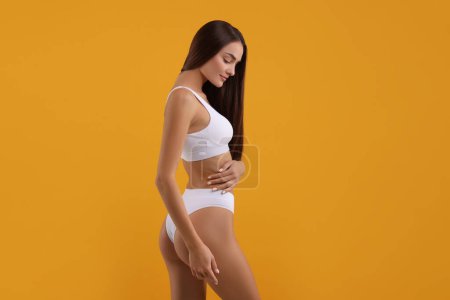 Foto de Mujer joven en bikini blanco con estilo sobre fondo naranja - Imagen libre de derechos