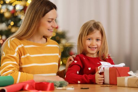 Envoltura de regalos de Navidad. Feliz madre y su pequeña hija en la mesa con cajas de regalo en la habitación