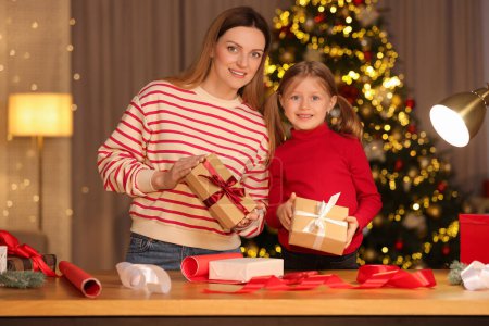 Envoltura de regalos de Navidad. Madre y su pequeña hija sosteniendo cajas de regalo en casa