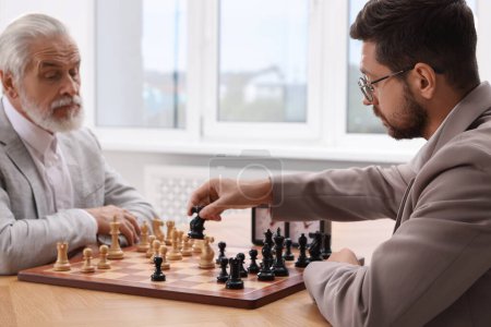 Hommes jouant aux échecs pendant le tournoi à la table à l'intérieur