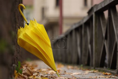 Autumn atmosphere. One yellow umbrella on city street, space for text
