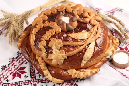 Korovai with wheat spikes on rushnyk, closeup. Ukrainian bread and salt welcoming tradition