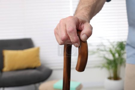 Senior man with walking cane at home, closeup. Space for text