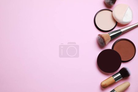 Different face powders and makeup brushes on pink background, flat lay. Space for text