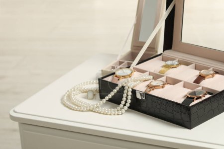 Cajas de joyería con muchos relojes de pulsera elegantes y collar de perlas en la mesa blanca. Espacio para texto