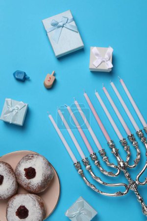 Photo for Flat lay composition with Hanukkah menorah and donuts on light blue background - Royalty Free Image