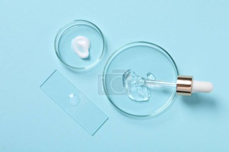 Photo for Petri dishes with samples of cosmetic serums and pipette on light blue background, flat lay - Royalty Free Image