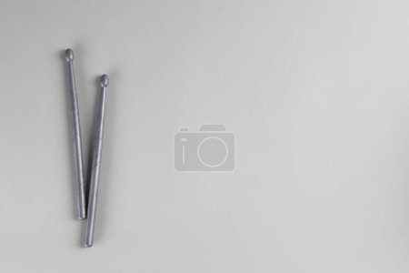 Two gray drum sticks on light background, top view. Space for text