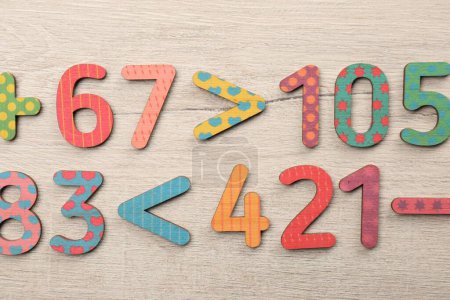 Photo for Colorful numbers and mathematical symbols on light wooden table, flat lay - Royalty Free Image