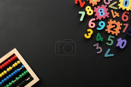 Photo for Many colorful numbers and mathematical symbols near abacus on black background, flat lay. Space for text - Royalty Free Image