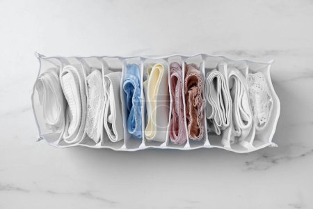 Photo for Organizer with folded women's underwear on white marble table, top view - Royalty Free Image