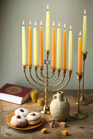 Composition with Hanukkah menorah, dreidels and donuts on wooden table against light background-stock-photo