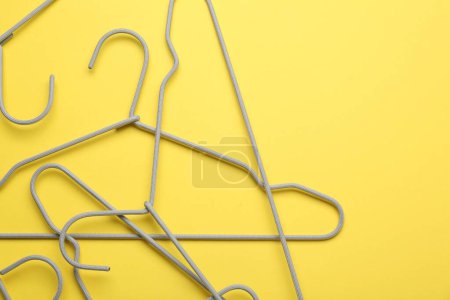 Photo for Empty hangers on yellow background, top view. Space for text - Royalty Free Image
