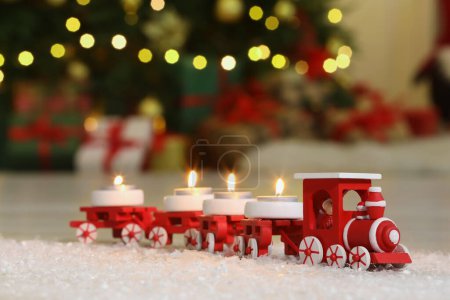 Téléchargez les photos : Train de jouets avec des bougies allumées près de l'arbre de Noël dans la chambre, gros plan. Espace pour le texte - en image libre de droit