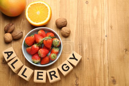 Alergia alimentaria. Nueces, fresas, cítricos y cubos sobre mesa de madera, tendido plano con espacio para texto