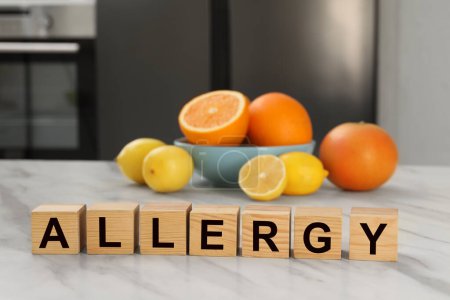 Alergia alimentaria. Cítricos frescos y cubos de madera sobre mesa de mármol blanco